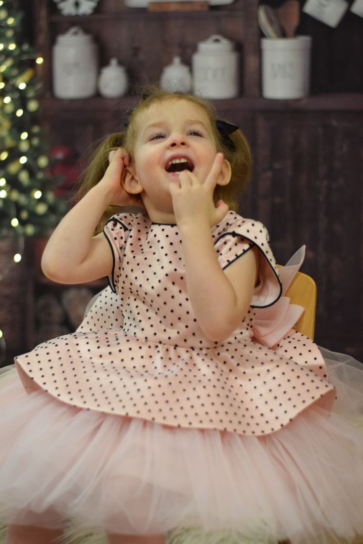 Mira riendo, con un vestido rosa de lunares